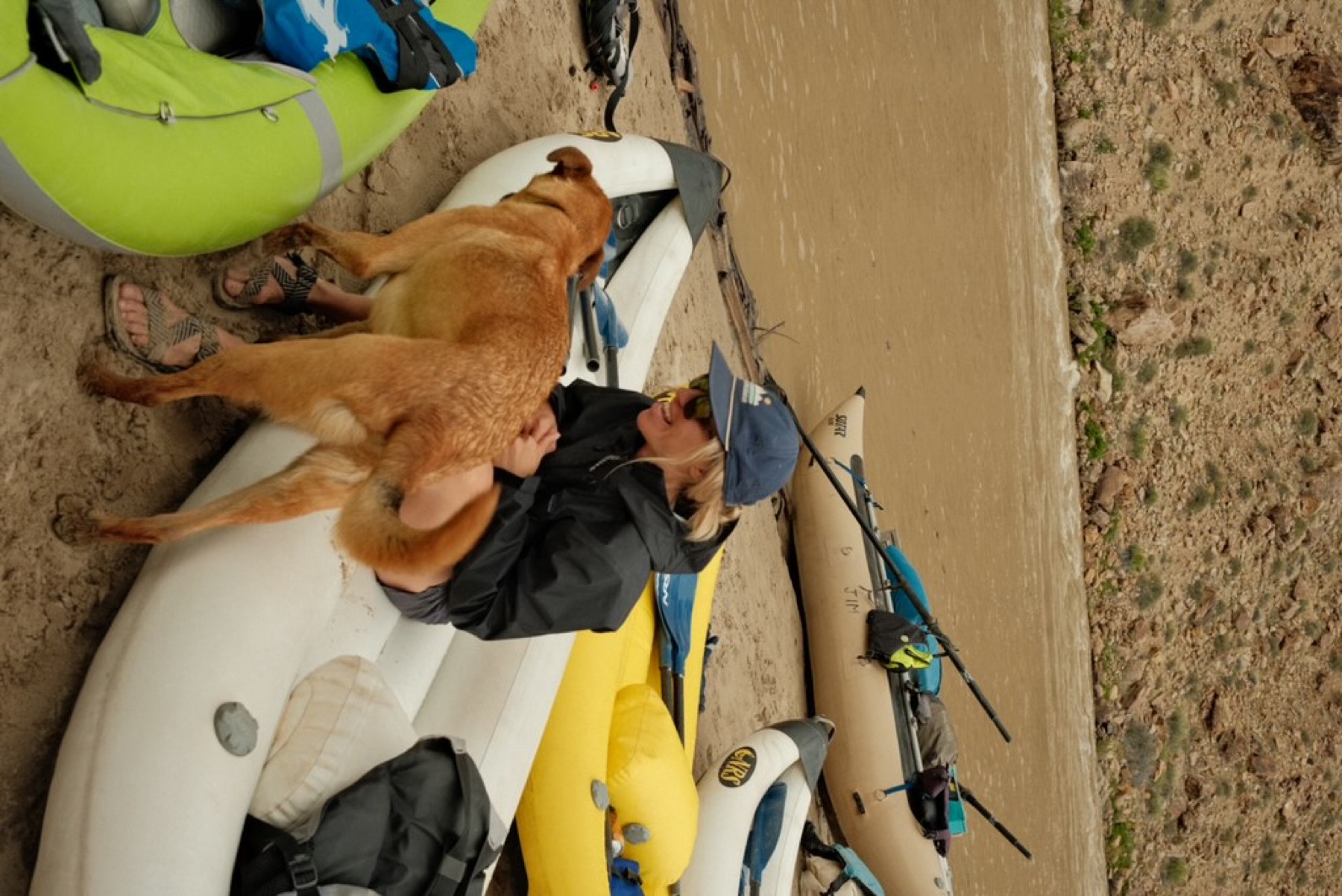 Tori Sowul sitting with a dog beside river rafts