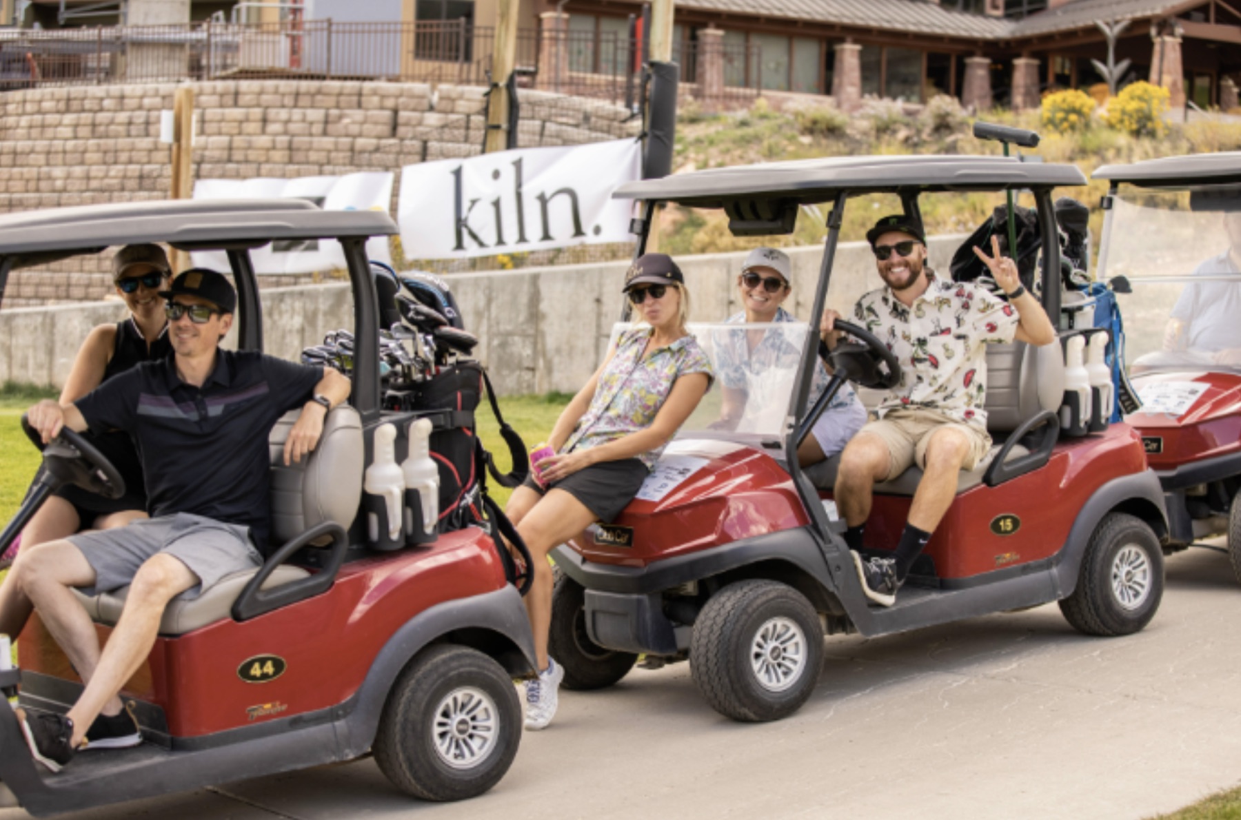 Kiln event guests riding golf carts in front of branded signage