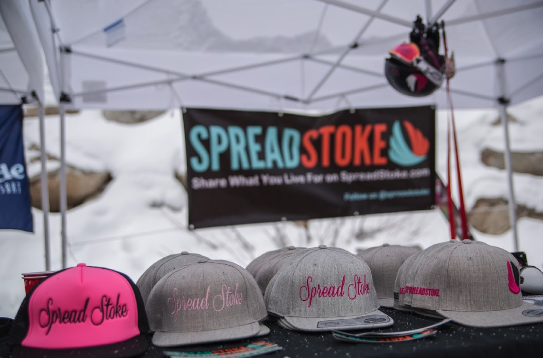 Spread Stoke hats displayed at an outdoor event booth
