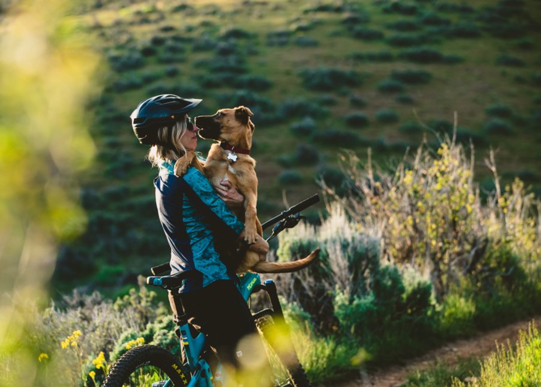 Tori Sowul wearing a bike helmet and holding her dog on a trail